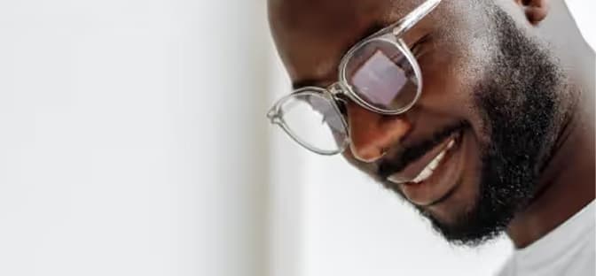 Close-up of a smiling man with clear-framed glasses