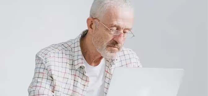 Man with beard wearing glasses focused on a laptop